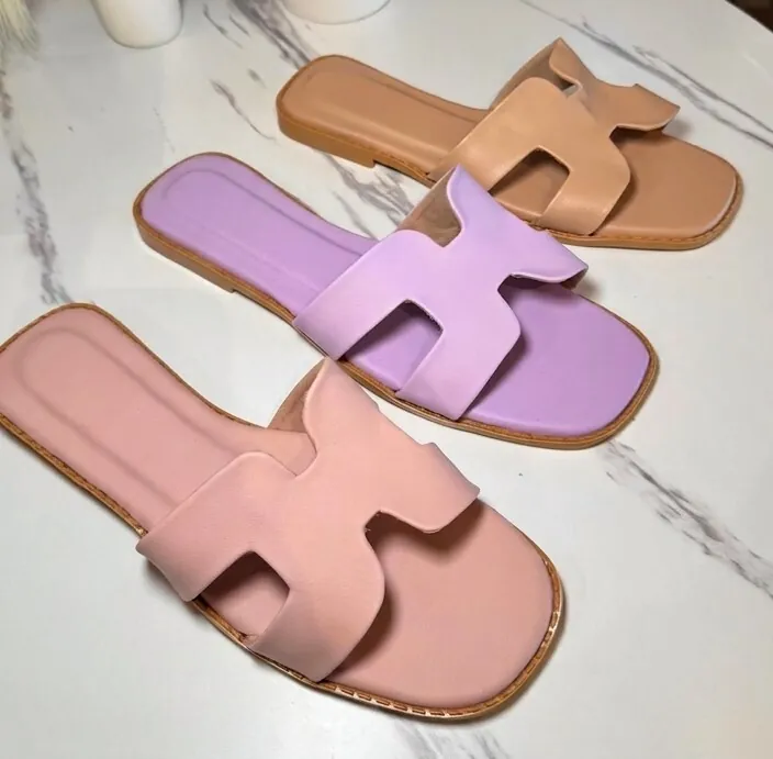 Blush, lilac, and nude leather slides arranged on marble